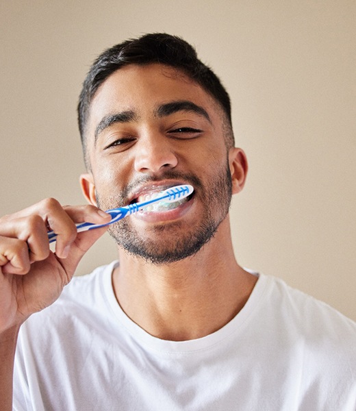 Man brushing teeth with white and blue toothbrush