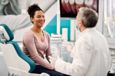 Happy African American woman and her dentist communicating at dentist's office.
